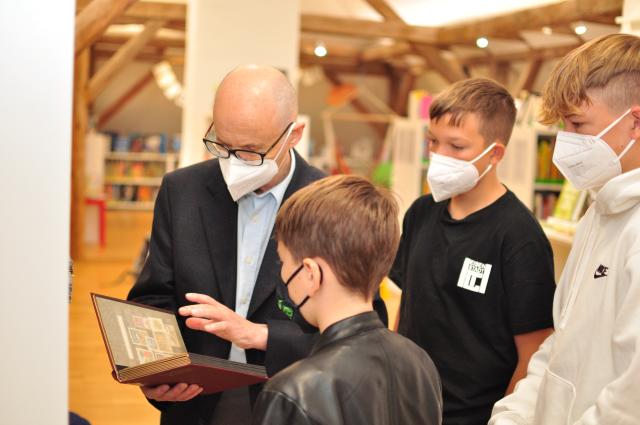 Johann Schleischitz zeigt Kindern Briefmarken. Philatelistische Jugendgruppe Hornstein